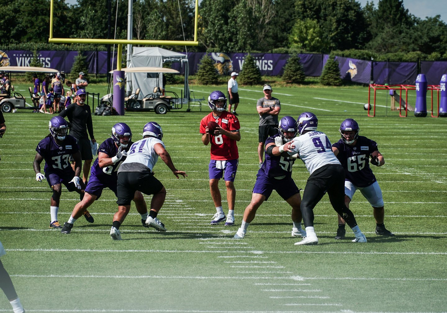 Football players in uniform practice drills on a grass field.