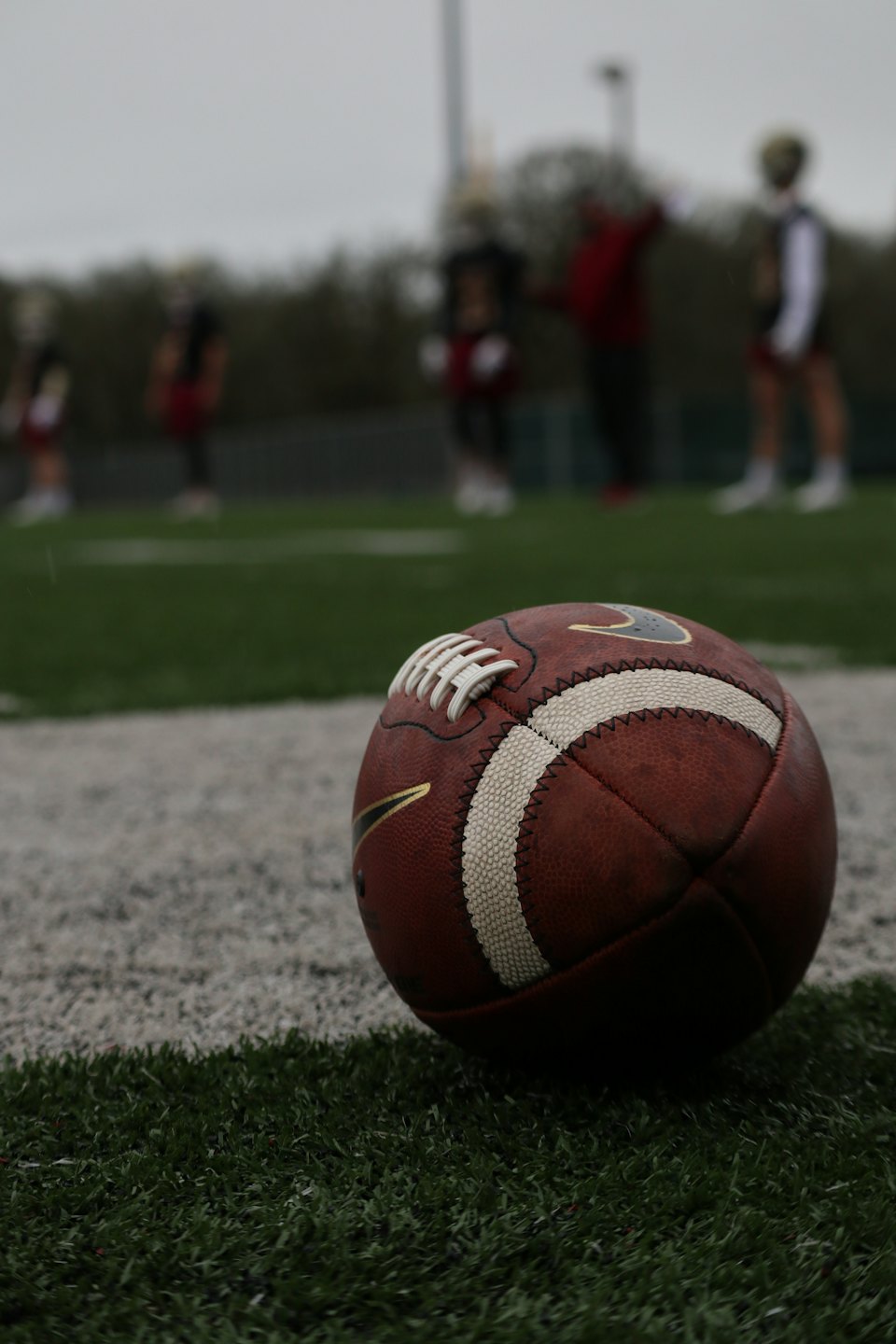 American football on sideline of green field.